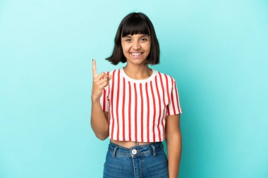 Mavi arka planda izole edilmiş genç melez kadın harika bir fikre işaret ediyor.