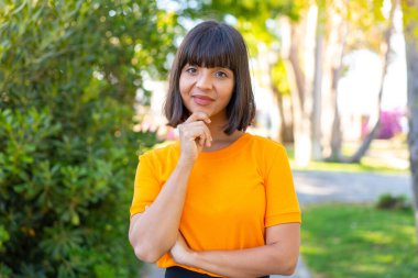 Parkta parktaki genç esmer kadın neşeli bir ifadeyle