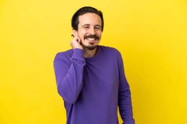 Sarı arka planda izole edilmiş genç beyaz adam gülüyor.