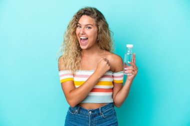 Mavi arka planda bir şişe suyu olan genç sarışın kadın zaferi kutluyor.