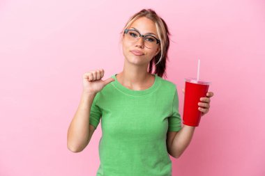 Genç Rus kadın pembe arka planda kendini beğenmiş ve gururlu bir ferahlatıcı tutuyor.