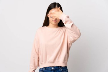 İzole edilmiş beyaz arka planı olan genç bir Çinli kız gözlerini elleriyle kapatıyor. Bir şey görmek istemiyorum.