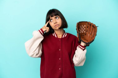 Beyzbol eldivenli genç melez kadın. Mavi arka planda izole edilmiş. Şüpheleri ve düşünceleri var.