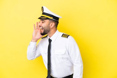 Arap uçak pilotu sarı arka planda izole edilmiş ve ağzı sonuna kadar açık bağırıyor.