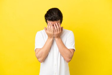 Sarı arka planda izole edilmiş, yorgun ve hasta bir ifadeyle genç beyaz bir adam.