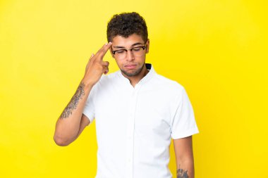 Yakışıklı Brezilyalı genç, sarı arka planda izole edilmiş intihar jesti yapmada sorun yaşıyor.