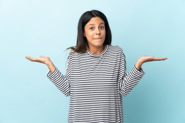 Mavi arka planda izole edilmiş beyaz kız ellerini kaldırırken şüpheleri var.