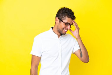 Genç yakışıklı Brezilyalı adam sarı arka planda izole edilmiş gülüyor.