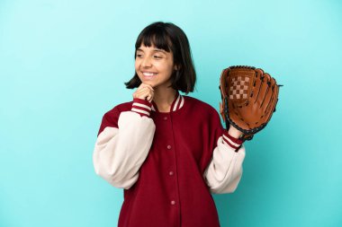 Beyzbol eldivenli, mavi arka planda soyutlanmış, yan tarafa bakan ve gülümseyen genç bir yarışçı kadın.