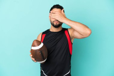 Rugby oynayan genç bir Arap, mavi arka planda tek başına, gözleri elleriyle kapatıyor. Bir şey görmek istemiyorum.