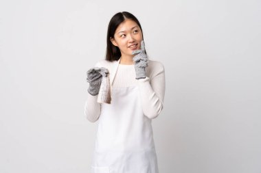 Çinli balıkçı önlük takıyor ve beyaz arka planda çiğ balık tutuyor.