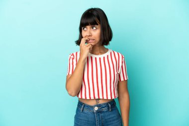 Mavi arka planda soyutlanmış genç melez bir kadın biraz gergin.