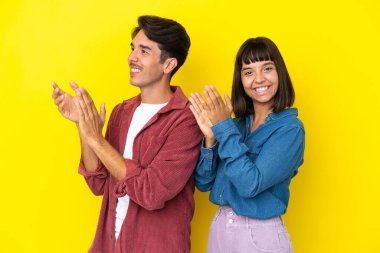 Genç melez çift sarı arka planda bir konferansta sunumdan sonra alkış tutuyorlar.