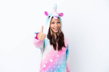 Beyaz arka planda tek boynuzlu at pijaması giyen genç bir Rus kadın. Başparmakları havada. Çünkü iyi bir şey oldu.