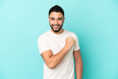 Genç Arap adam mavi arka planda tek başına zaferi kutluyor.