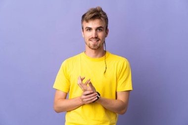 Genç yakışıklı sarışın adam mor arka planda yalnız gülüyor.