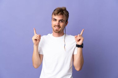 Mor arka planda izole edilmiş yakışıklı sarışın adam harika bir fikre işaret ediyor.