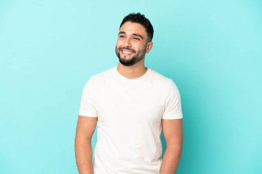 Genç Arap adam mavi arka planda izole edilmiş bir şekilde bakarken bir fikir düşünüyor.