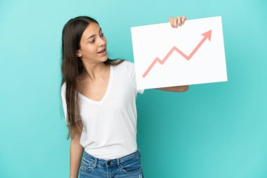 Mavi arka planda izole edilmiş genç bir Fransız kadın elinde büyüyen bir istatistik oku sembolü ve mutlu ifadeli bir tabela tutuyor.