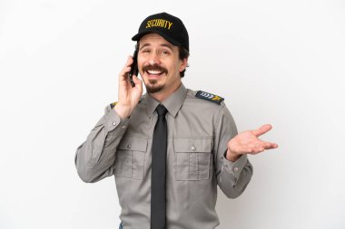 Beyaz arka planda izole genç bir beyaz güvenlik görevlisi cep telefonuyla sohbet ediyor.