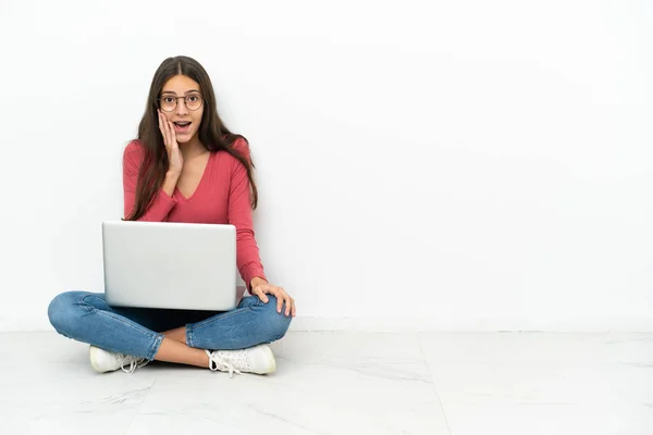 年轻的法国姑娘带着她的笔记本电脑坐在地板上 脸上带着惊讶和震惊的表情 — 图库照片