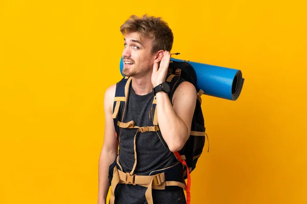 Ung Bergsklättrare Man Med Stor Ryggsäck Isolerad Gul Bakgrund Lyssna — Stockfoto