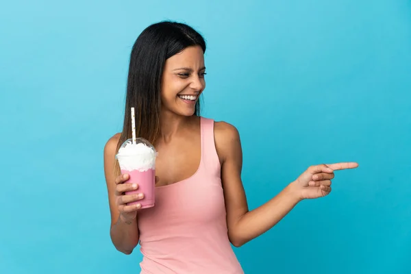 イチゴミルクセーキの指を横に向けて製品を提示している若い女性 — ストック写真