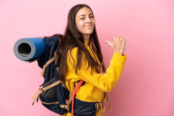 若い登山家の女の子とともに大きなバックパックピンクの背景に孤立誇りと自己満足 — ストック写真