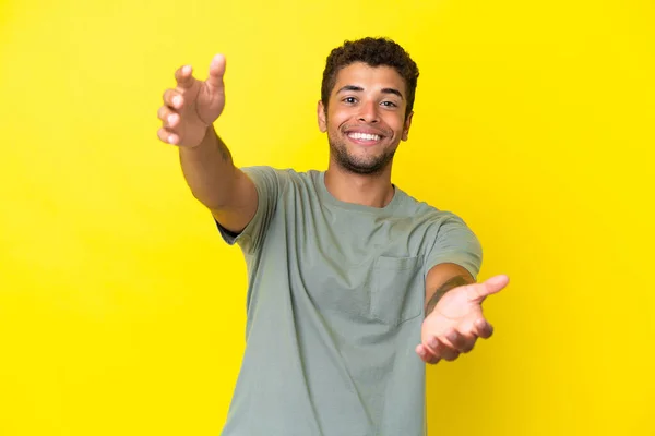 Młody Przystojny Brazylijczyk Odizolowany Żółtym Tle Prezentuje Zaprasza Ręki — Zdjęcie stockowe