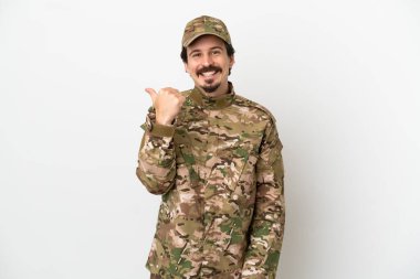Beyaz arka planda izole edilmiş asker bir ürün sunmak için kenarı işaret ediyor.