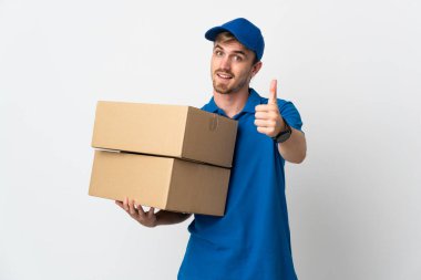 Genç teslimatçı sarışın adam beyaz arka planda izole edildi. Başparmakları havada çünkü iyi bir şey oldu.