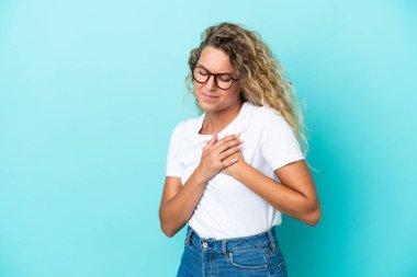 Mavi arka planda izole edilmiş kıvırcık saçlı bir kızın kalbi ağrıyor.