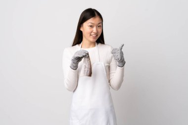 Çinli balıkçı önlük takıyor ve beyaz arka planda çiğ balık tutuyor.