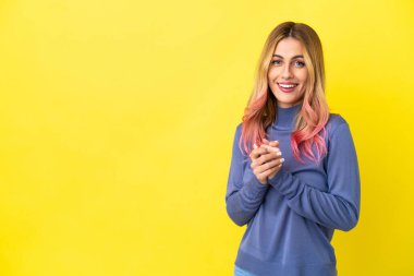 Sarı arka planda yaşayan genç bir kadın gülüyor.