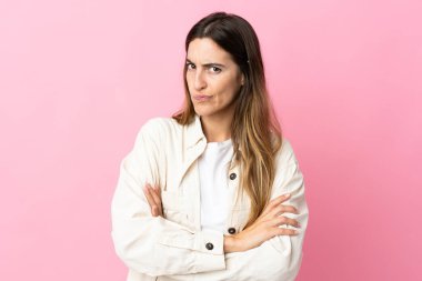 Pembe arka planda izole edilmiş genç beyaz kadın üzgün hissediyor.