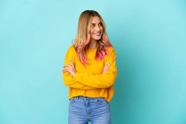 Soyutlanmış mavi arka planda genç bir kadın yan tarafa bakıyor.