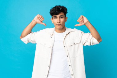 Arjantinli genç adam arka planda iki eliyle baş parmağını gösteriyor.