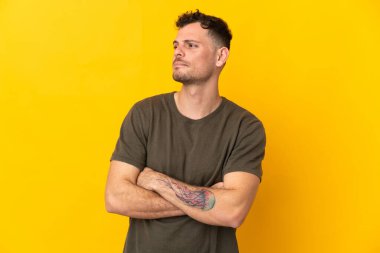 Sarı arka planda izole edilmiş beyaz, yakışıklı genç adam yan tarafa bakıyor.