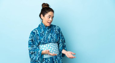 Kimono giyen bir kadın, yalıtılmış arka planda sürpriz bir ifadeyle yan tarafa bakarken...