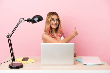 Pembe arka planda dizüstü bilgisayarı olan genç bir bayan öğrenci.