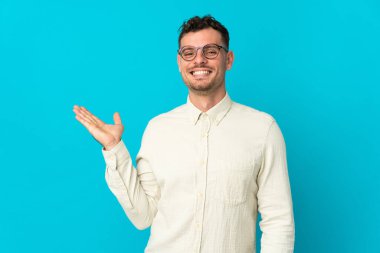 Beyaz tenli yakışıklı, mavi arka planda izole edilmiş bir adam. Elinde bir ilan vermek için fotokopi odası hayali var.