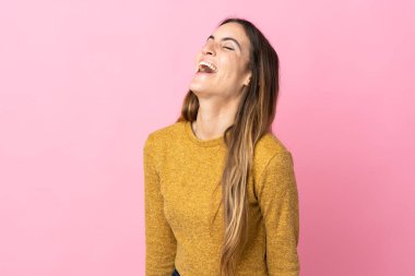 Pembe arka planda izole edilmiş genç beyaz kadın gülüyor.