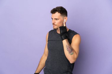 Mor arka planda izole edilmiş beyaz, yakışıklı bir adam müzik dinliyor.