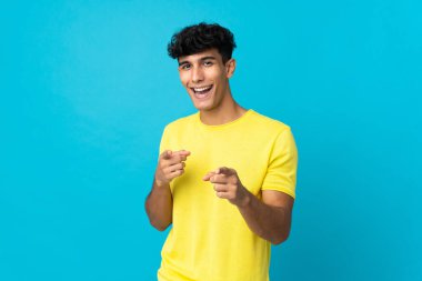 Arjantinli genç adam arka planda izole edilmiş şaşırmış ve ön tarafı işaret ediyor.