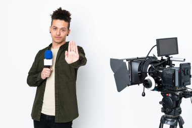 Muhabir elinde mikrofon, elinde haberlerle elinde jestleri durduruyor.