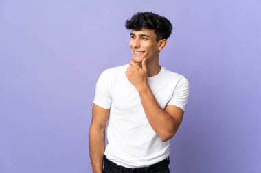 Arjantinli genç adam arka planda izole edilmiş, yana bakıyor ve gülümsüyor.