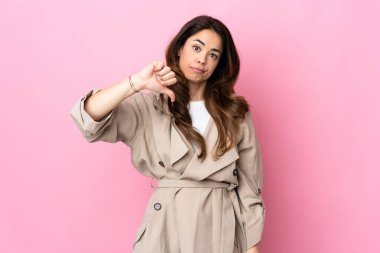 İzole edilmiş arka planda, olumsuz ifadeyle baş parmağını gösteren kadın.