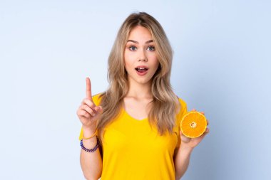Mavi arka planda portakal tutan genç Rus kız harika bir fikre işaret ediyor.