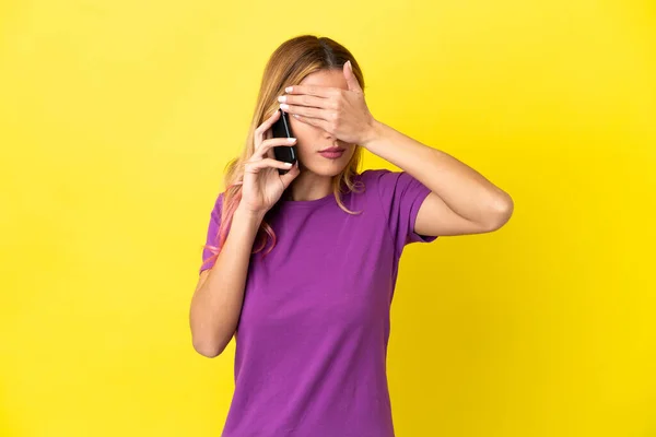 Mladá Žena Pomocí Mobilního Telefonu Přes Izolované Žluté Pozadí Zakrývající — Stock fotografie