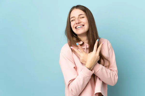 Jonge Kaukasische Vrouw Geïsoleerd Blauwe Achtergrond Glimlachen Tonen Overwinning Teken — Stockfoto